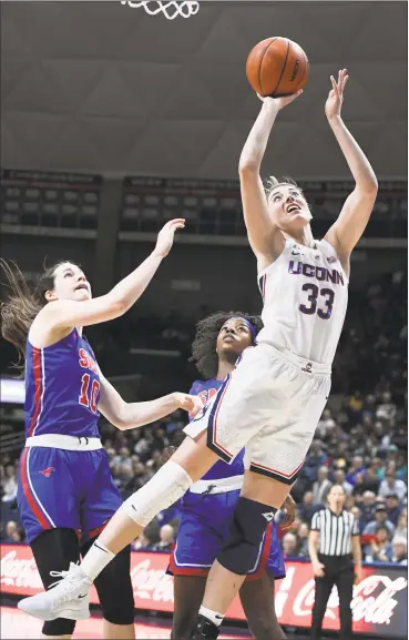  ?? Jessica Hill / Associated Press ?? UConn’s Katie Lou Samuelson shoots next to SMU’s Alicia Froling, left, and Kayla White during Wednesday’s 79-39 win in Storrs. Samuelson scored 21 points.