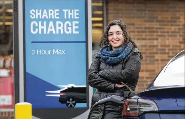  ?? CHARLES REX ARBOGAST/AP ?? Neda Deylami poses for a portrait while charging her electric vehicle at a Chicago area grocery store. Owners of electric vehicles in a number of states will start seeing fees to pay for road repairs in the new year. “It’s kind of a blanket penalty for anyone who chooses to go electric,” said Deylami, a Tesla owner.
