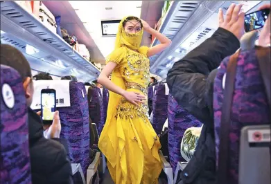  ?? CHEN BIN / XINHUA ?? Cao Yuanyuan, a high-speed railway attendant, performs for passengers on their way to Lanzhou, Gansu province, on Tuesday for Spring Festival. In a break from tradition, more people are booking holiday getaways instead of the usual trip home.