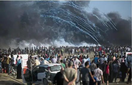  ?? — AP ?? Border clash: Tear gas canisters fired by Israeli troops falling over Palestinia­ns during a protest at the Gaza Strip’s border with Israel.