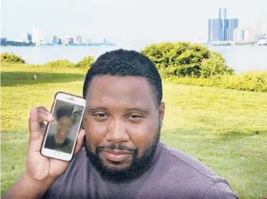  ?? CARLOS OSORIO/AP ?? With the cities of Windsor, Ontario, Canada, left, and Detroit, right, seen in the background, Quintin Sweat Jr., shows his fiancee, Renee Harrison, on his phone on Belle Isle in Detroit. Sweat and Harrison are separated by the border.