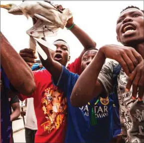  ?? EDUARDO SOTERAS/AFP ?? A man holds a bird as a crowd gathers to protest in the neighbourh­ood of Yolo in Kinshasa yesterday.