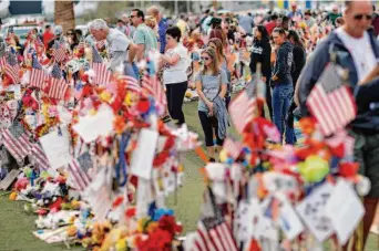  ?? John Locher / Associated Press 2017 ?? People visit a makeshift memorial honoring the victims of the Oct. 1, 2017, mass shooting in Las Vegas. Fifty-eight people were killed and more than 850 were injured by a lone gunman.