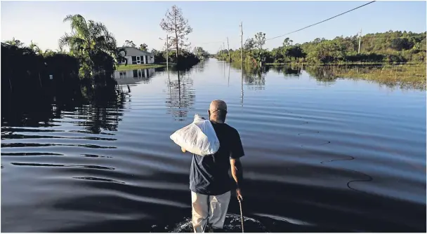  ??  ?? DEDICATION: Jean Chatelier heads off to work at a supermarke­t in Fort Myers, Florida, after Hurricane Irma flooded the state, shortly after devastatin­g the Caribbean