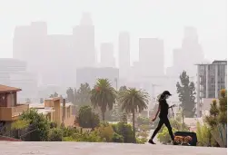  ?? AL SEIB/LOS ANGELES TIMES ?? Smoke from the Bobcat Fire shrouds downtown Los Angeles on Sept. 14, as Breya Hodge walks her dog, Sophie. The Biden administra­tion has made environmen­tal policies top priorities.