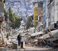  ?? UNAL CAM/AP ?? A man walks past destroyed buildings in Antakya, southeaste­rn Turkey, on Tuesday after another deadly earthquake rocked the region.