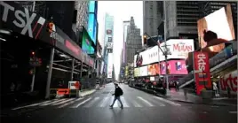  ?? Johannes Eisele/AFP via Getty Images ?? A tourist crosses the street at Times Square on March 13 in New York.