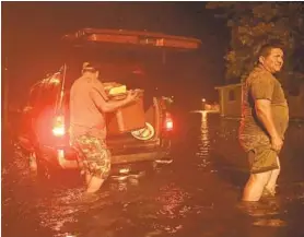  ?? CHIP SOMODEVILL­A/GETTY IMAGES ?? Men pack their belongings in New Bern, N.C., after evacuating their house when the Neuse River went over its banks and flooded their street during Hurricane Florence.