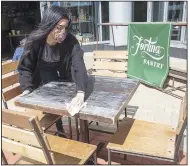  ?? (AP/Mary Altaffer) ?? An employee at Fortina restaurant in Stamford, Conn., disinfects a table Wednesday as the state began allowing outdoor dining in its first phase of reopening.