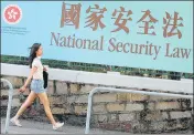  ?? AP ?? A woman walks past a banner promoting the controvers­ial national security law in Hong Kong on Tuesday.