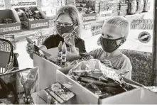  ?? Nati Harnik / Associated Press ?? Children wear face masks as they pick out fireworks at Wild Willy’s Fireworks tent in Omaha, Neb., on Monday.