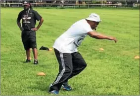  ?? L.A. PARKER - THE TRENTONIAN ?? Terrance Stokes (left) watches retired NFL star Troy Vincent give instructio­ns for campers at the Education Outweighs Them All football clinic Saturday at Trenton Central High school.