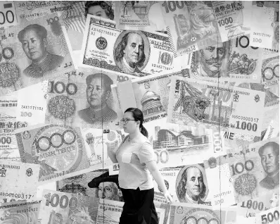  ?? AP ?? A woman walks by a money exchange shop decorated with different countries’ currency banknotes at Central, a business district in Hong Kong, Tuesday, August 6, 2019.