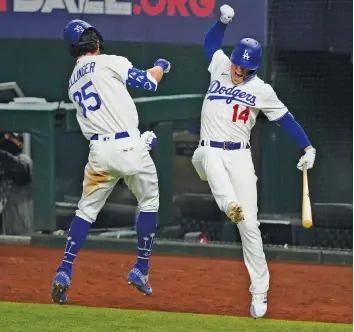  ?? TONY GUTIERREZ/ASSOCIATED PRESS ?? Cody Bellinger and Enrique Hernandez celebrate Bellinger’s seventh inning home run that gave the Los Angeles Dodgers a 4-3 lead over the Atlanta Braves in Game 7 of the National League Championsh­ip Series on Sunday.