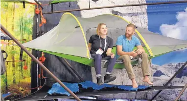  ?? RICK BOWMER/ASSOCIATED PRESS ?? Vanessa Castagnoli of Tentsile shows Eric Hanson the Stingray tree tent at the Outdoor Retailer show last week in Salt Lake City. Hybrid hammock-tents that allow people to sleep under the stars or chill out while dangling from the trees are growing in popularity among enthusiast­s who are embracing the idea of these treehouses.