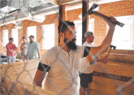  ??  ?? Andrew Shafer, left, from Dallas, and friend Eric Were throw axes at the Downtown Art Gallery and Axe Room last weekend in Denver. When completed later this summer, the venue will have several throwing cages. Andy Cross, The Denver Post