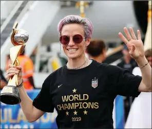  ?? AP/KATHY WILLENS ?? Megan Rapinoe displays the Women’s World Cup trophy after the team arrived Monday at Newark Liberty Internatio­nal Airport in Newark, N.J.