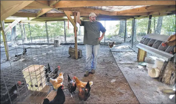  ?? HYOSUB SHIN / HSHIN@AJC.COM ?? Brian Maloof, owner of Manuel’s Tavern in Atlanta, takes a short break as he feeds chickens at the 9-acre farm he bought in Jasper last year. His wife, Margie, describes the farm as Brian’s “happy place.”