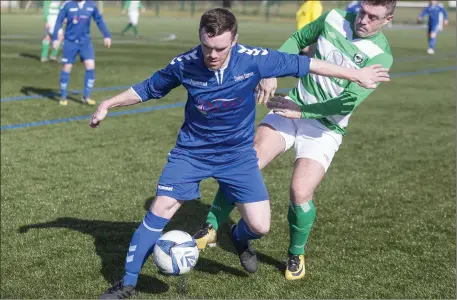  ??  ?? Carbury’s Ross McLoughlin shields the ball from Strand Celtic’s Simon Martin in their Super League clash . Photos: Donal Hackett.