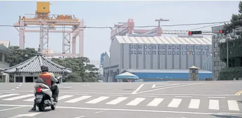  ??  ?? A man on a motorbike waits for a traffic signal in front of Hyundai Heavy Industries’ shipyard in Ulsan. The letter reads ‘Our success is the success of the country, and the success of the country is the way we go well.’