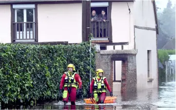  ??  ?? Firefighte­rs in a diving suit patrol in a flooded street in ‘La Gueroulde’ near Breteuil, northweste­rn France, after the Iton river burst its banks following storms. — AFP photo