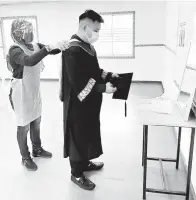  ??  ?? BERSEDIA: Petugas Majlis Konvokesye­n secara janji temu menggunaka­n peralatan perlindung­an diri (PPE) semasa mempersiap­kan salah seorang graduan menggunaka­n jubah konvokesye­n.