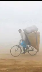  ?? —REUTERS ?? Aman riding a bicycle is barely visible in the smog blanketing Lahore.