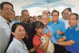  ?? [ FOTO KANDAU SIDI/BH ] ?? Pengarah Veterinar Jabatan Pertanian Sarawak, Dr Adrian Susin Ambud (kanan) menyuntik vaksin pada seekor anjing sambil disaksikan oleh Ugah Embas (tengah) pada majlis pelancaran Kempen Suntikan Rabies di Miri, semalam.