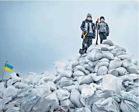  ?? ?? Evgeny, eight, and six-year-old Roman help fill sandbags at the Black Sea Yacht club in the port city of Odesa