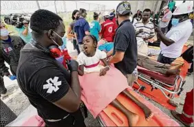  ?? Wilfredo Lee / Associated Press ?? A young girl is examined after arriving Friday at Port-au-prince-toussaint Louverture Internatio­nal Airport from a medical evacuation flight. She was injured in the Aug. 14 magnitude 7.2 earthquake in Haiti.