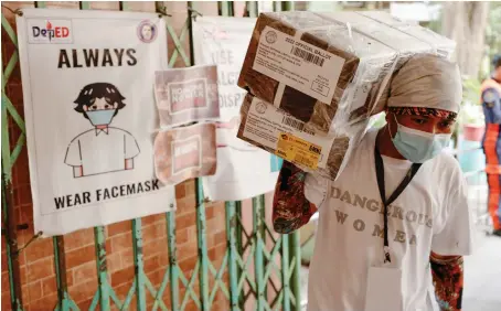  ?? Reuters ?? A worker carries ballot boxes for Monday’s election as they arrive at an elementary school that is used as a polling precinct in Manila on Sunday.