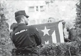  ?? Francisco Seco Associated Press ?? A MAN holds a Catalan independen­ce f lag in front of a policeman outside the National Court. Catalan leaders have accused Madrid of robbing their region.