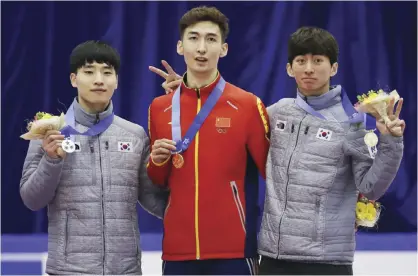  ?? — AP ?? SAPPORO: Gold medalist Wu Dajing, center, of China is flanked by silver medalist Seo Yi-ra, left, of South Korea and Park Se-yeong, of South Korea during the victory ceremony of the men’s 500 meters of short track speed skating competitio­n at the Asian...
