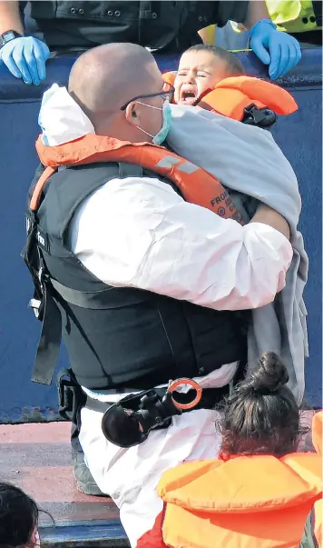  ??  ?? A Border Force official cradles a baby, one of a number of small children and toddlers taken into care in Dover