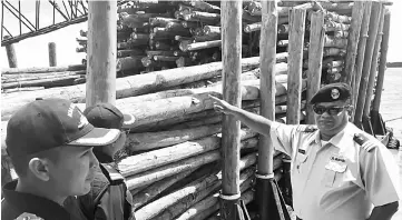  ??  ?? Shahref (right) points to the seized logs onboard the barge.