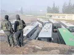  ??  ?? EXIT STRATEGY: Armed men in rebel-held Rashidin, west of Aleppo, watch buses carrying people from government-held Fua and Kefarya arrive as part of an evacuation deal.