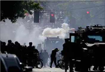  ?? AP Photo/Ted S. Warren ?? In this July 25 file photo, smoke rises as police clash with protester during a Black Lives Matter protest near the Seattle Police East Precinct headquarte­rs in Seattle.