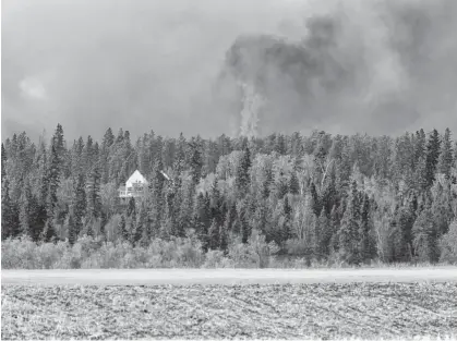  ?? REUTERS FILE ?? Wildfires burn near a house as the city of Prince Albert, Sask. declared a state of emergency over a fast-moving wildfire, prompting some residents to evacuate, on May 18.