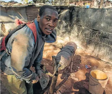  ?? Picture: Simphiwe Nkwali ?? Thami Gqola (23), an illegal miner, crushes stones with a makeshift crusher to extract gold at the Makulu Gama squatter camp in Krugersdor­p, Gauteng. More than 2,700 illegal miners were arrested between 2013 and 2017, and almost 1,200 mine employees were arrested for aiding them.