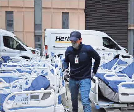  ?? SPENCER PLATT/GETTY IMAGES ?? Crews prepare dozens of extra medical beds Tuesday after they were delivered to Mount Sinai Hospital in New York City, where the coronaviru­s pandemic has left hospitals facing severe shortages.