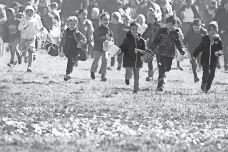  ?? PHOTOS BY ERIC SEALS/DETROIT FREE PRESS ?? Kids run toward marshmallo­ws dropped from a helicopter during the 39th Wayne County Parks Marshmallo­w Drop at Nankin Mills in Westland on Friday.