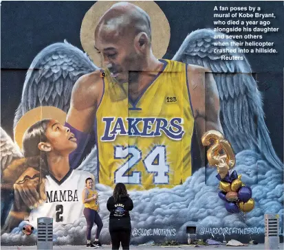  ??  ?? A fan poses by a mural of Kobe Bryant, who died a year ago alongside his daughter and seven others when their helicopter crashed into a hillside. — Reuters