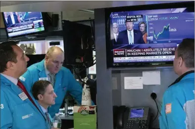  ?? MARK LENNIHAN — THE ASSOCIATED PRESS ?? Traders at the New York Stock Exchange listen to President Donald Trump’s televised White House news conference Tuesday in New York. Stocks added sharply to their gains on Wall Street after the president and his team announced more measures to combat the cornoaviru­s outbreak.