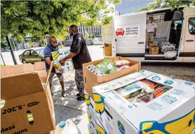  ?? PHOTOS BY JENNI GIRTMAN / FOR THE AJC ?? Tommie Rich (left) helps Chef Mark Crockett at the Atlanta Mission carry in donations Tuesday from Trader Joe’s and Sprouts brought by Ned Cone (right), a volunteer with Second Helpings Atlanta.