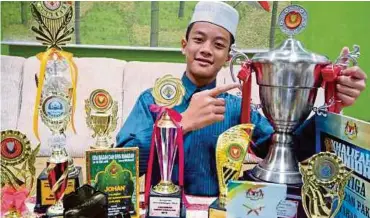  ??  ?? Wan Ahmad Nur Firas bersama hadiah pertanding­an hafazan dan tilawah al-quran.