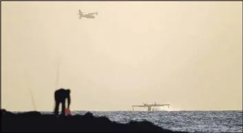  ?? ARIEL SCHALIT/THE ASSOCIATED PRESS ?? Firefighti­ng planes load water from the Mediterran­ean sea off the coast near Netanya, Israel, on Saturday. Fires raging in the nation for a fifth day burned 40 homes in a Jewish West Bank settlement.