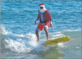  ?? The Associated Press ?? In this photo from the Florida Surf Museum, a man dressed in a Santa Claus costume surfs in Cocoa Beach, Fla., on Wednesday. The annual Surfing Santa Day was forced to become an online event this year.