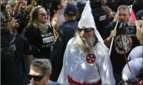  ?? STEVE HELBER — THE ASSOCIATED PRESS ?? This July 8 photo shows members of the KKK escorted by police past a large group of protesters during a KKK rally in Charlottes­ville, Va. Some white Southerner­s are again advocating for what the Confederac­y tried and failed to do in the 1860s:...