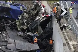  ?? VAGGELIS KOUSIORAS — THE ASSOCIATED PRESS ?? Workers supported by a crane try to remove train-crash debris from the rail lines in Tempe, near Larissa city, Greece, on Thursday.