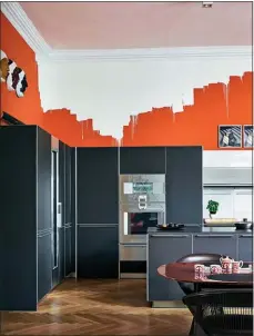  ??  ?? A pink ceiling and bold splash of orange paint highlight a modern, monotone kitchen.